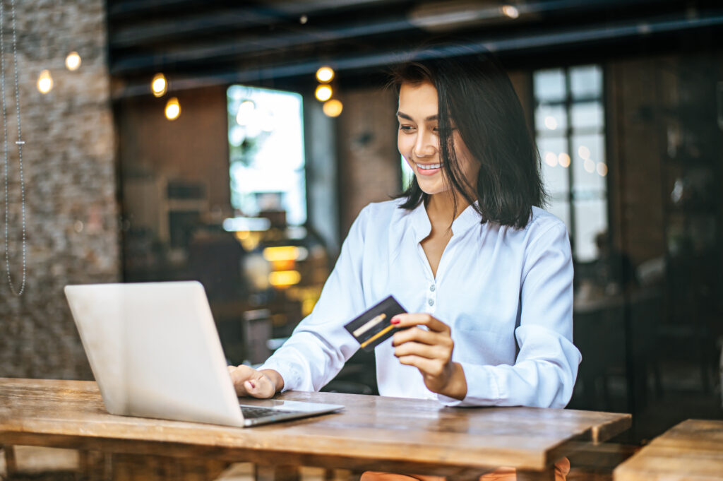 woman sat with laptop paid with credit card cafe